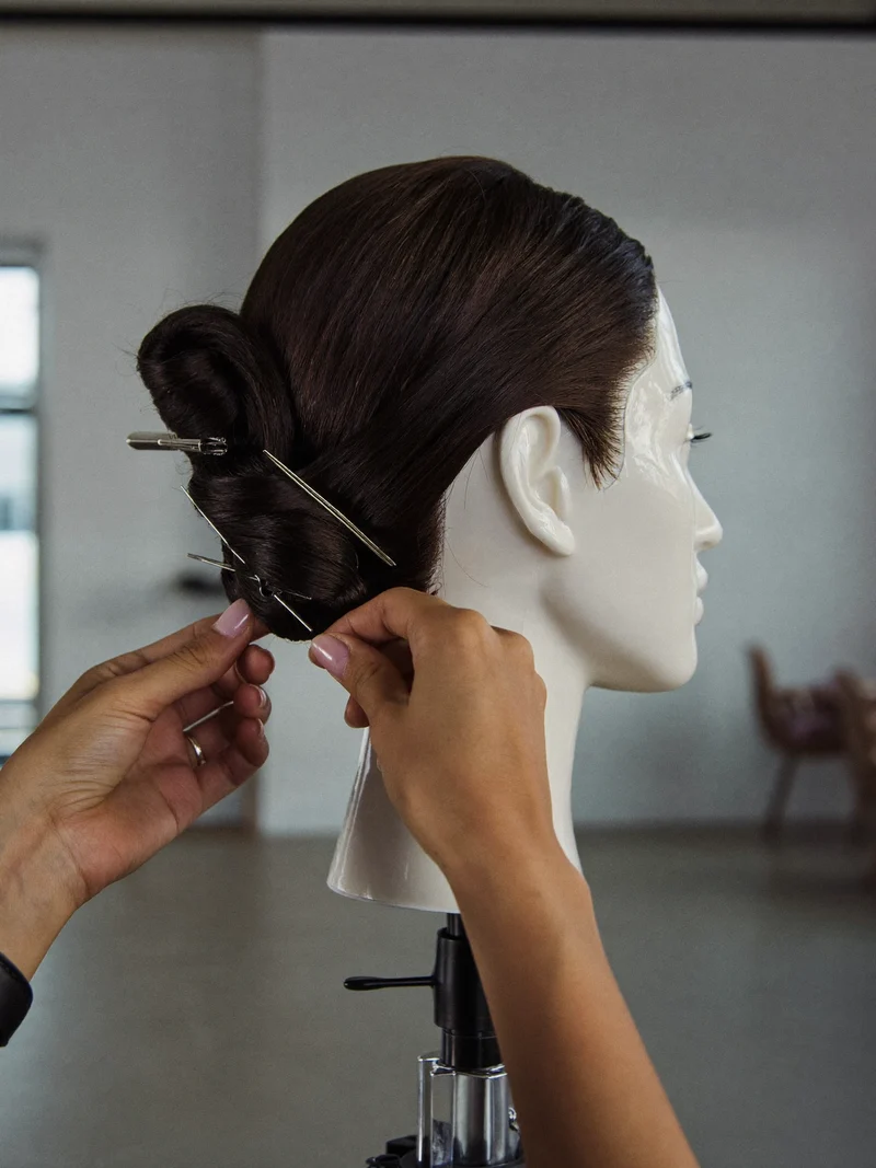 Chignon bas sculpté, épinglé avec précision sur une tête d'étude
